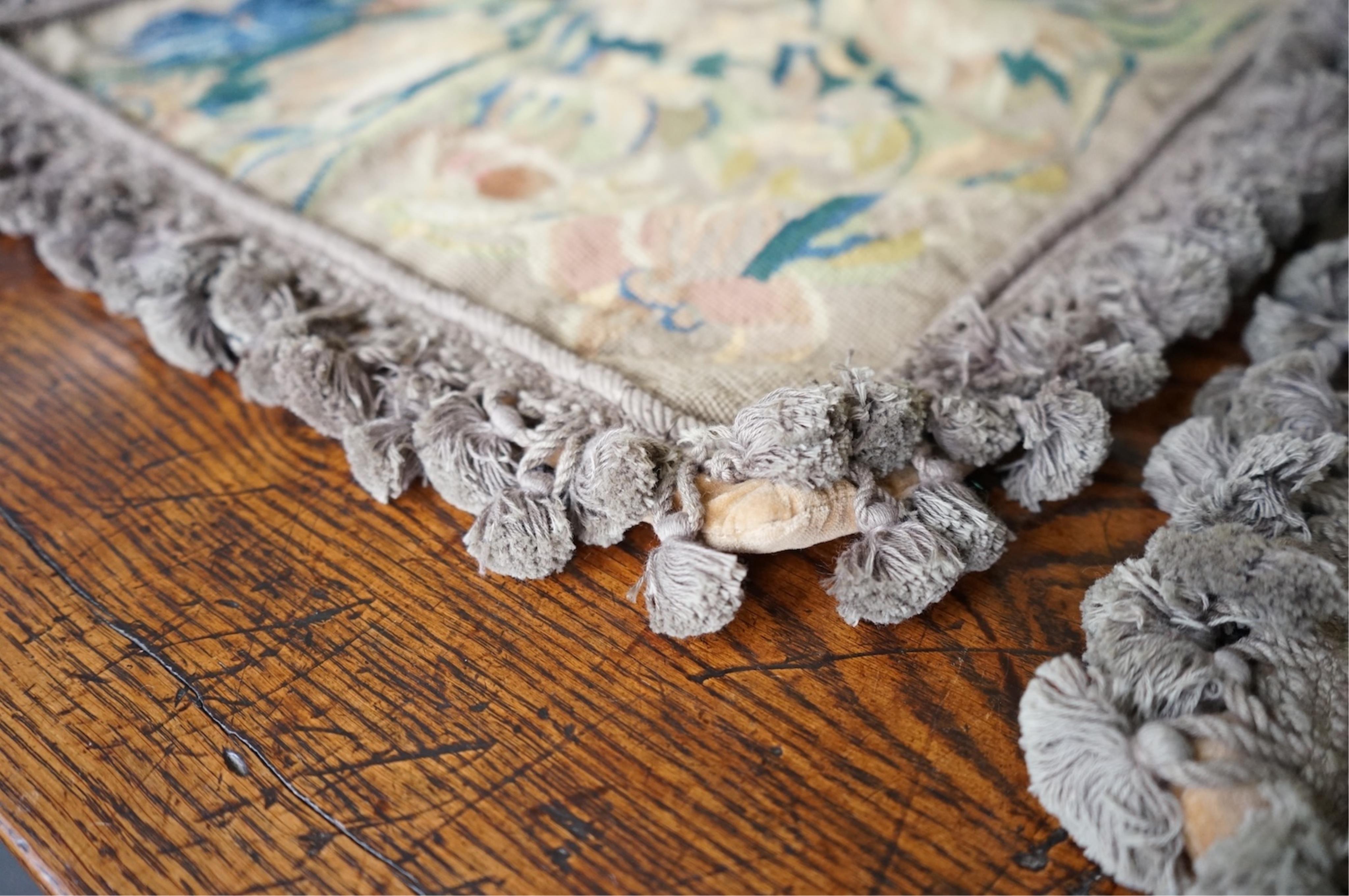 Four large rectangular wool worked cushion covers, with a still life design of a bowl of roses, tulips and daffodils. Embroidered in very muted colours, with ornate tasseled braid and velvet backing. 48cm high x 39cm wid
